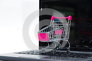 Shopping cart or supermarket trolley with laptop notebook on white background, e-commerce and online shopping concept.