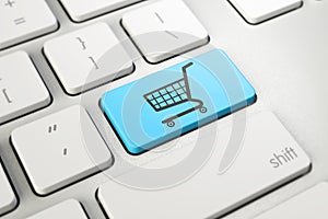 Shopping cart symbol on blue button key of white keyboard, online shopping