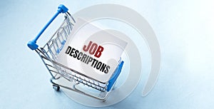 Shopping cart and text JOB DESCRIPTIONS on white paper note list. Shopping list concept on blue background