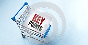 Shopping cart and text key points on white paper note list. Shopping list concept on blue background