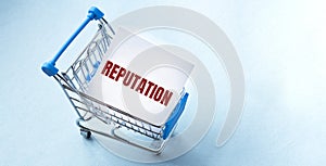 Shopping cart and text REPUTATION on white paper note list. Shopping list concept on blue background