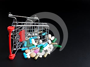 Shopping carts overthrow colorful medicine on black background