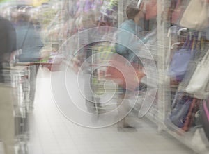 Shopping center, shop mall store. Woman in supermarket with shopping basket, retail. Abstract defocused motion blurred