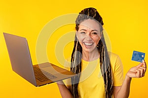 Shopping on computer. Smiling woman with laptop and credit card making purchase online.