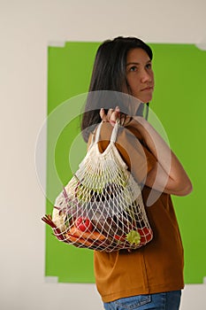 Shopping, consumerism and people concept - smiling young woman with food in bag at home