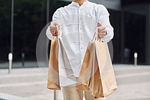 Shopping day. Stylish young man is outdoors with bags