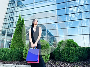 Shopping day. Woman holding colored bags near her shooping mall in black friday holiday