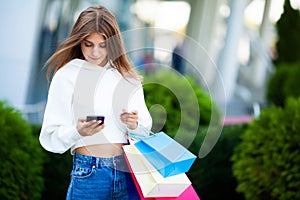 Shopping day. Woman holding colored bags near her shooping mall in black friday holiday.