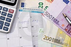 Shopping day written in the planner with euro bills,