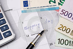 Shopping day written in the planner with euro bills,