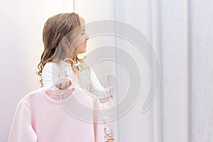 Shopping. discounts. little girl shopaholic. girl trying on a beautiful dress gently pink in the fitting room of the boutique. sho