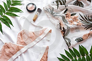 Shopping and fashion concept. Set of glamorous stylish lace lingerie with green leaves and woman accessories on white bed bac