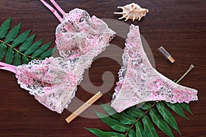 Shopping and fashion concept. Set of glamorous stylish lace lingerie lying on dark wooden background with flowers. Flatlay, w