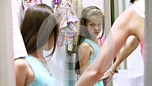 Shopping. in fitting room of large store, pretty, serious girl, a kid tries on new outfits, chooses what to buy. The