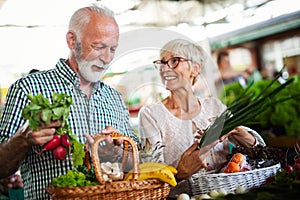 Shopping, food, sale, consumerism and people concept - happy senior couple buying fresh food