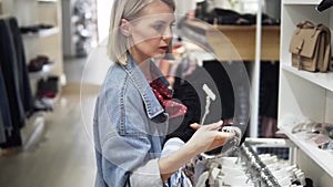 Shopping girl. Portrait of a beautiful woman in the clothes store. Young blonde girl with red lips in a clothing store