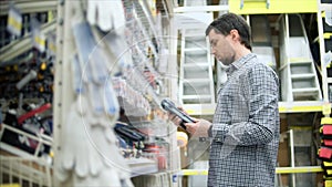 Shopping in hardware store. Man near shelf with tools and instruments