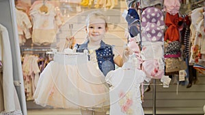 Shopping for kids. The girl shows in the frame hangers with outfits