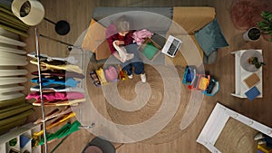 Top view close up shot of young girl on the couch in the living room, female holding clothes she ordered online, box and