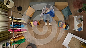 Top view close up shot of young man on the couch in the living room holding smartphone, showing new clothes to friends