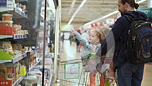 Shopping list food crises concepts. Father with Two daughters at Supermarket. Children sitting in cart. Kids Siblings