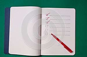 Shopping list with multiple items. Open notebook on green background photo
