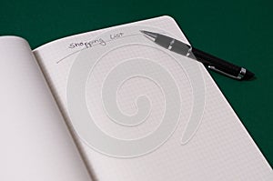 Shopping list with multiple items. Open notebook on green background photo