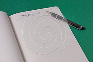 Shopping list with multiple items. Open notebook on green background photo