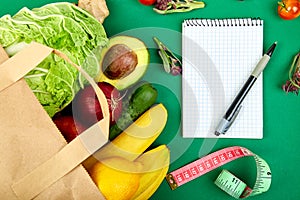 Shopping list, recipe book, diet plan. Grocering concept. Full paper bag of different fruits and vegetables, ingredients for