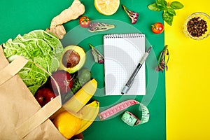 Shopping list, recipe book, diet plan. Grocering concept. Full paper bag of different fruits and vegetables, ingredients for