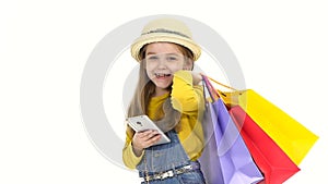 Shopping Little girl holding a mobile phone bags and looking at him and smiling. Slow motion