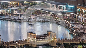 Shopping mall exterior with reataurants near fountain in Dubai downtown aerial night timelapse, United Arab Emirates