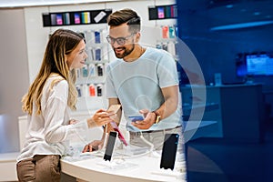 Shopping a new digital device. Happy couple buying a smartphone in store.