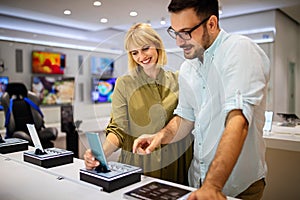 Shopping a new digital device. Happy couple buying a smartphone in store.