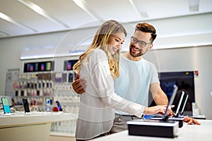 Shopping a new digital device. Happy couple buying a smartphone in store.