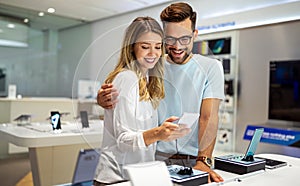 Shopping a new digital device. Happy couple buying a smartphone in store.