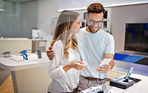 Shopping a new digital device. Happy couple buying a smartphone in store.