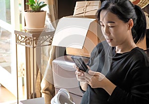 shopping online concept. asian young woman sitting using smartphone online shopping parcel and buying fashion items.