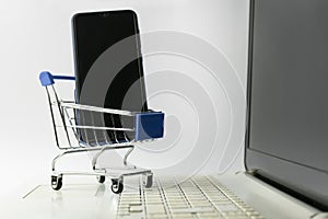 Shopping online concept.Supermarket mini shopping trolley with a phone on laptop.E-commerce with smart phone ,online technology