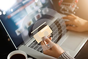 Shopping online concept. Woman holding gold credit card in hand and online shopping using on laptop at home