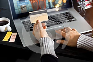 Shopping online concept. Woman holding gold credit card in hand and online shopping using on laptop at home