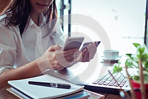 shopping online concept. Young woman holding credit card and mobile smart phone on bed