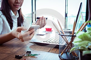 shopping online concept. Young woman holding credit card and mobile smart phone on bed