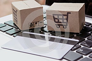Shopping online. Credit card and cardboard box with a shopping cart logo on laptop keyboard