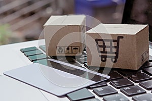 Shopping online. Credit card and cardboard box with a shopping cart logo on laptop keyboard
