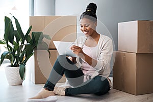 Shopping online for things to put in her new home. Shot of a young woman using a digital tablet while moving house.