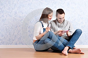 Shopping online together. Beautiful young loving couple shopping online while sitting on the floor together