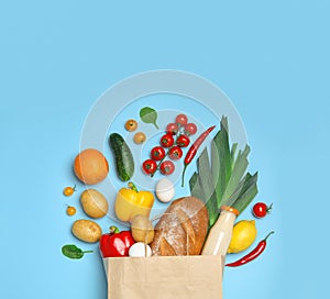 Shopping paper bag with  groceries on light blue background, flat lay