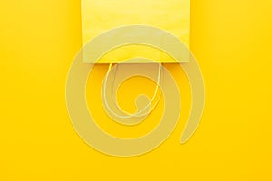 Shopping paper bag on the yellow background with copy space. flat lay photo of upturned yellow bag. summer sale concept