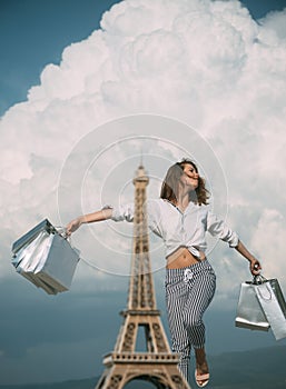 Shopping in Paris. Happy woman after shopping rejoices purchases. Fashion woman near Eiffel Tower in France. Trendy girl